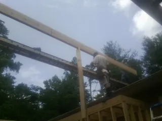 Carpenter setting a ridge beam over a new addition frame — Ice Dam Removal by Roofing Brothers in Brookeville