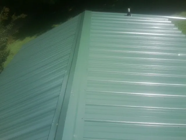 New green metal panels meeting at the ridge of a roof — Flat Roof Repair work by our crew in Brookeville