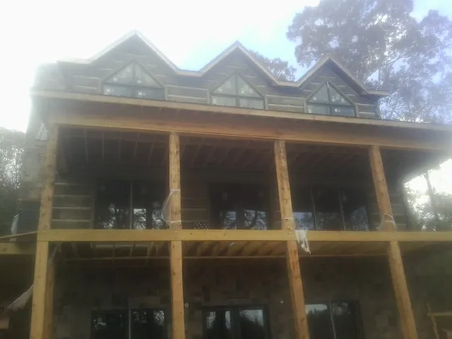 Dormers and porch framing on a large log home under construction — Roof Coating work by our crew in Brookeville