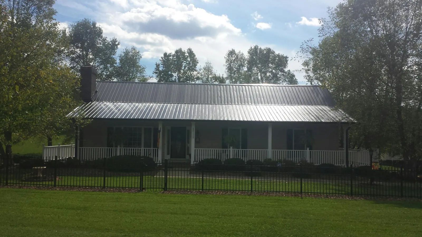 Gray metal roof on a brick ranch with a full width front porch — Gutter Guard Installation work by our crew in Brookeville