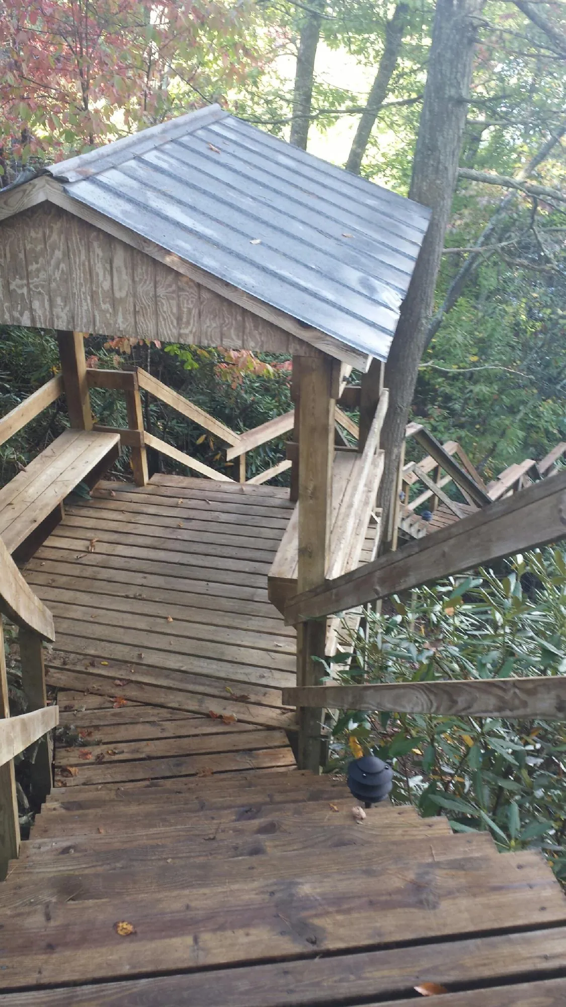 Metal roofed shelter over wooden steps on a wooded walkway — Skylight Repair & Installation work by our crew in Brookeville